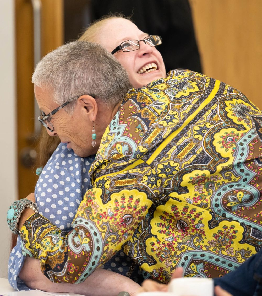 This photograph shows two women in a happy embrace.  These are ONSIDE volunteers Lynda and Jackie who are meeting in person for the first time.