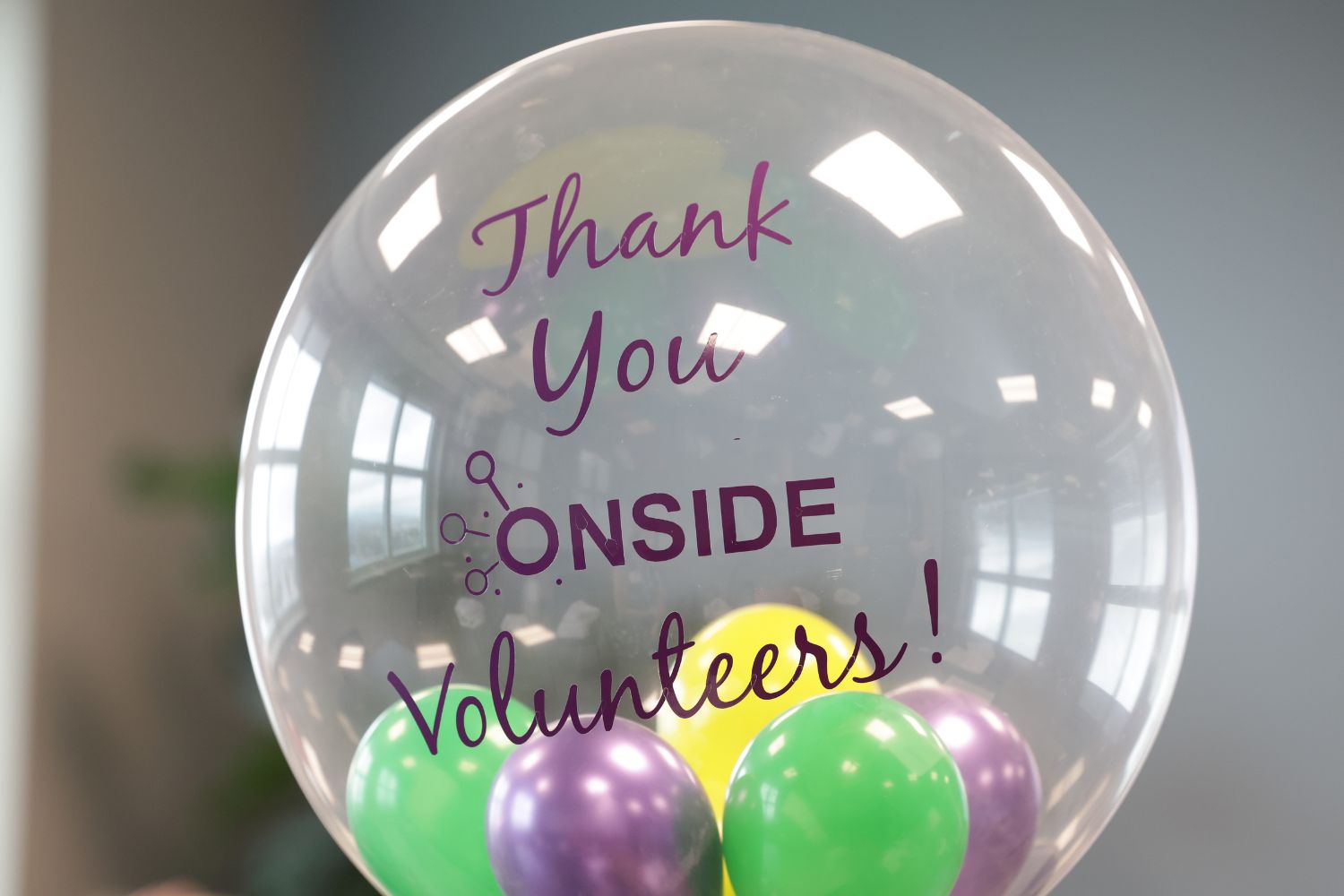 The photograph shows a close up shot of a transparent balloon with smaller coloured balloons inside it, the caption on the balloon says Thank You ONSIDE Volunteers!
